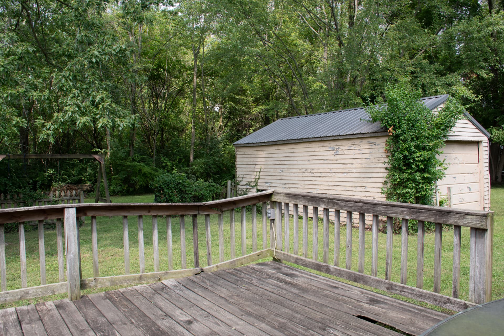 View from the deck toward the detached outbuilding and tree line