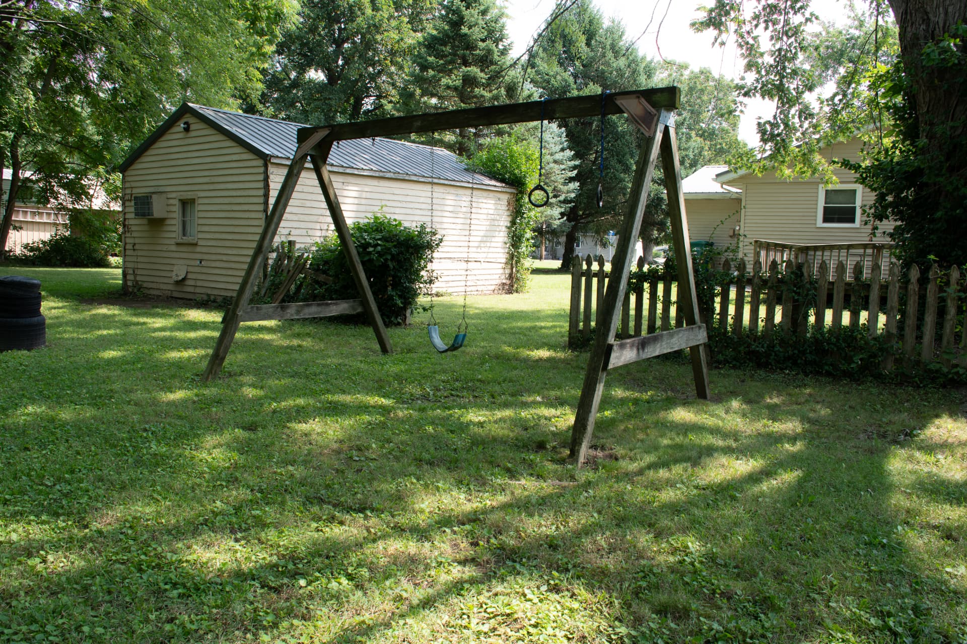 Backyard with swing set and outbuilding photographed for a real estate listing