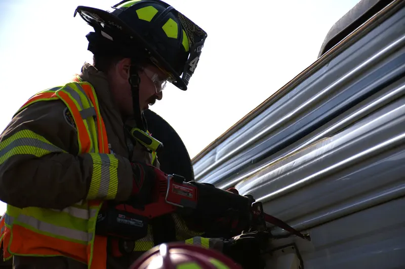 A firefighter cuts into the side of a camper with a reciprocating saw during extrication training.
