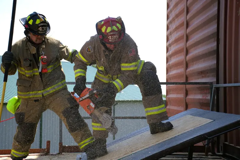 Two firefighters cut a roof ventilation prop with a rotary saw.