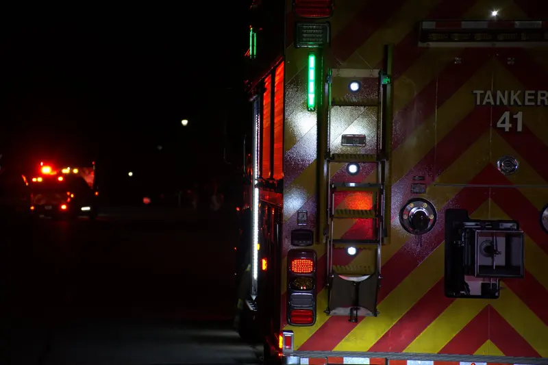 The rear of Tanker 41 at night, its red and yellow chevrons lit by scene lights.